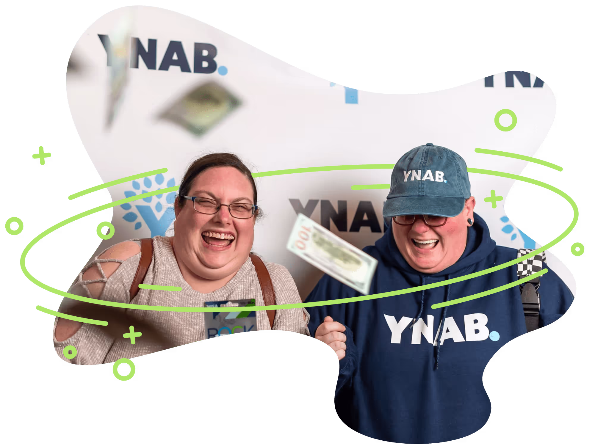 Two women standing in front of a YNAB-themed step and repeat laughing